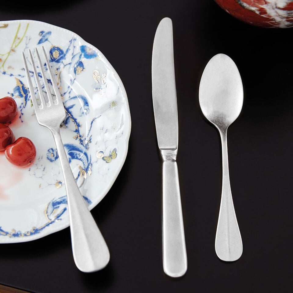 Baguette cutlery on a black table and close to a little dish